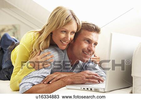 Couple Using Laptop Relaxing Sitting On Sofa At Home View Large Photo Image Stock Image - Couple Using Laptop Relaxing Sitting On Sofa At Home. Fotosearch