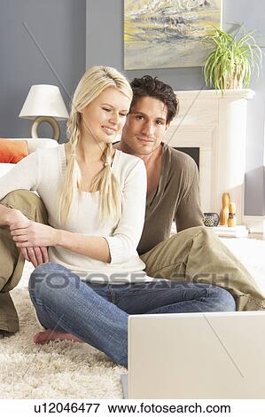 Couple Using Laptop Relaxing Sitting On Rug At Home View Large Photo Image Stock Photo - Couple Using Laptop Relaxing Sitting On Rug At Home. Fotosearch