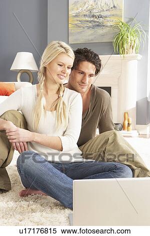 Couple Using Laptop Relaxing Sitting On Rug At Home View Large Photo Image Stock Photography - Couple Using Laptop Relaxing Sitting On Rug At Home. Fotosearch