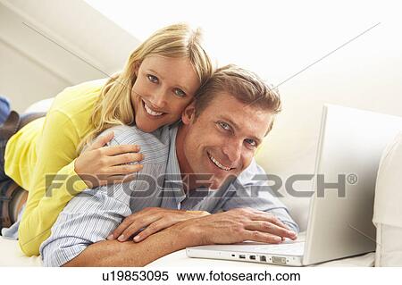 Couple Using Laptop Relaxing Sitting On Sofa At Home View Large Photo Image Stock Photography - Couple Using Laptop Relaxing Sitting On Sofa At Home. Fotosearch