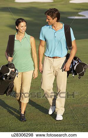 Couple Walking Along Golf Course Carrying Bags View Large Photo Image Stock Photo - Couple Walking Along Golf Course Carrying Bags. Fotosearch