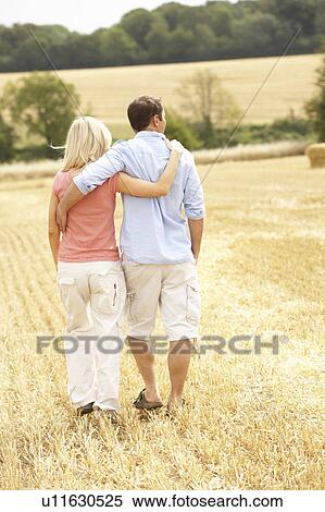 Stock Photography - Couple Walking Together Through Summer Harvested Field. Fotosearch