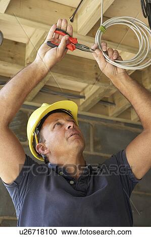 Stock Image - Electrician Working On Wiring In New Home. Fotosearch