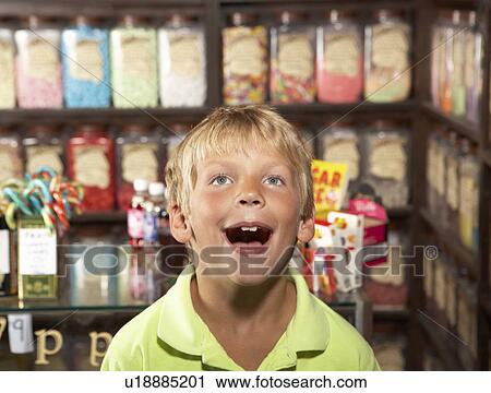 Stock Image - Excited Boy Standing In Sweet Shop. Fotosearch