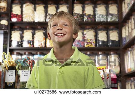 Stock Photograph - Excited Boy Standing In Sweet Shop. Fotosearch