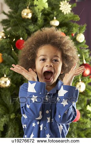 Stock Image - Excited Young Boy In Front Of Christmas Tree. Fotosearch