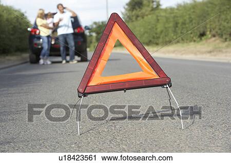 Stock Image - Family Broken Down On Country Road With Hazard Warning Sign In Foreground. Fotosearch