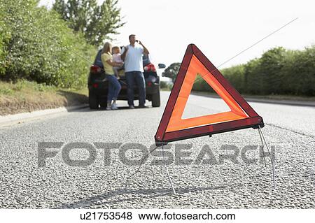 Stock Photo - Family Broken Down On Country Road With Hazard Warning Sign In Foreground. Fotosearch