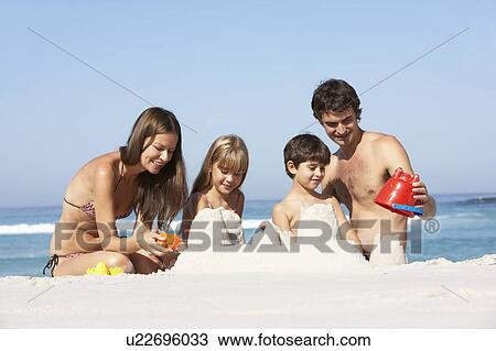 Stock Image - Family Building Sandcastles On Beach Holiday. Fotosearch