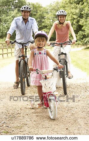Stock Photograph - Family Cycling In Countryside Wearing Safety Helmets. Fotosearch