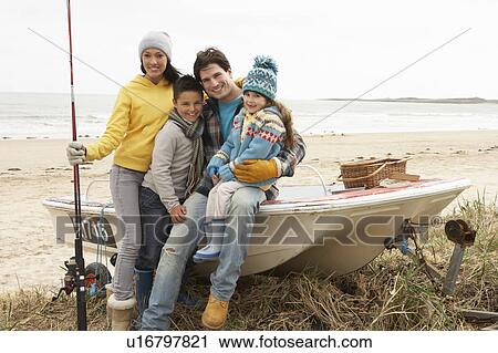 Stock Image - Family Group Sitting On Boat With Fishing Rod On Winter Beach. Fotosearch