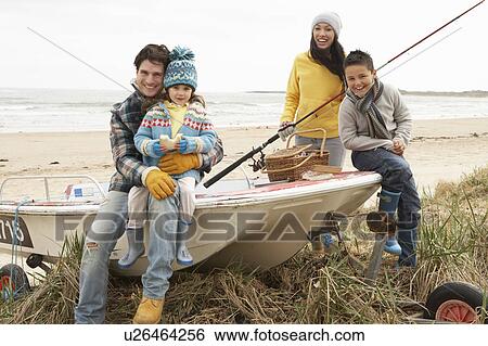 Stock Photograph - Family Group Sitting On Boat With Fishing Rod On Winter Beach. Fotosearch