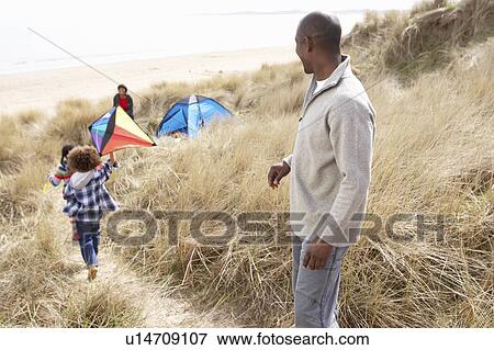 Stock Photo - Family Having Fun With Kite In Sand Dunes. Fotosearch