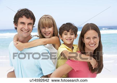 Stock Image - Family Having Piggyback Fun On Beach Holiday. Fotosearch