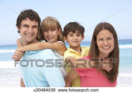 Stock Photo - Family Having Piggyback Fun On Beach Holiday. Fotosearch