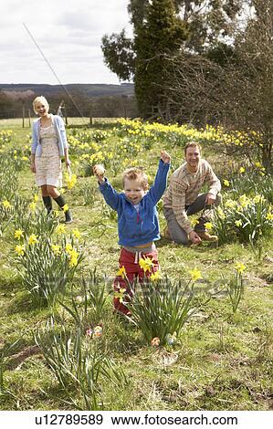 Stock Photo - Family On Easter Egg Hunt In Daffodil Field. Fotosearch
