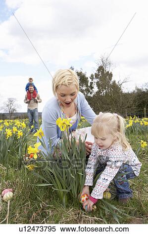 Stock Photography - Family On Easter Egg Hunt In Daffodil Field. Fotosearch