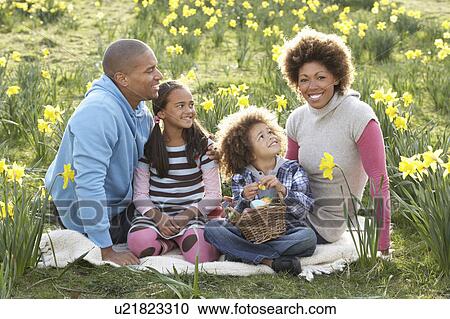 Stock Image - Family Relaxing In Field Of Spring Daffodils. Fotosearch