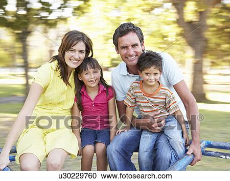 Stock Image - Family Riding On Roundabout In Park. Fotosearch