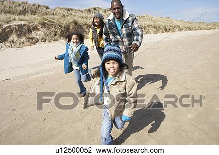 Stock Image - Family Running On Winter Beach. Fotosearch