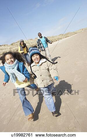 Stock Image - Family Running On Winter Beach. Fotosearch