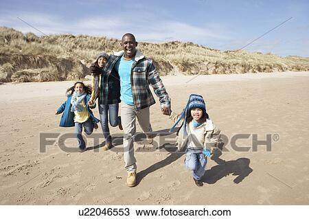 Stock Image - Family Running On Winter Beach. Fotosearch