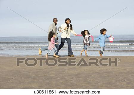 Stock Image - Family Running On Winter Beach. Fotosearch