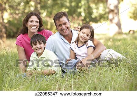 Stock Photo - Family Sitting In Long Grass In Park. Fotosearch