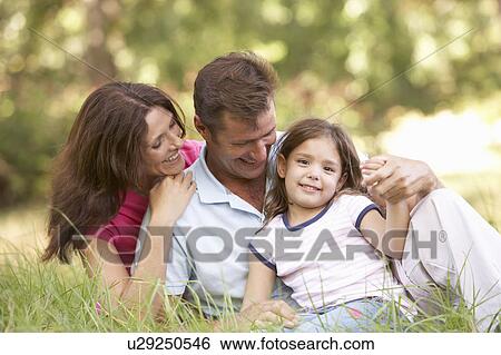 Stock Photograph - Family Sitting In Long Grass In Park. Fotosearch
