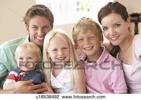 Stock Image - Family Sitting On Sofa At Home Together. Fotosearch
