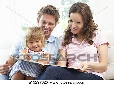 Stock Photography - Family Sitting On Sofa Reading Book At Home. Fotosearch
