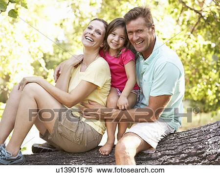 Stock Photograph - Family Sitting On Tree In Park. Fotosearch