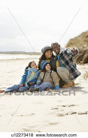 Stock Photo - Family Sitting On Winter Beach. Fotosearch