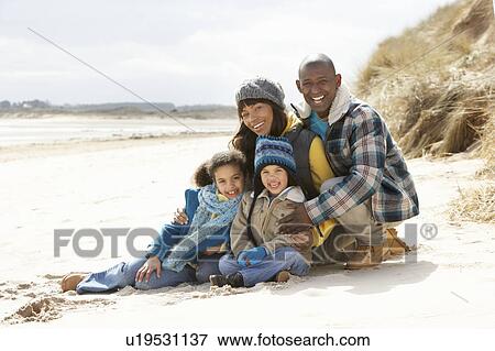 Stock Photo - Family Sitting On Winter Beach. Fotosearch