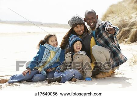 Stock Photograph - Family Sitting On Winter Beach. Fotosearch
