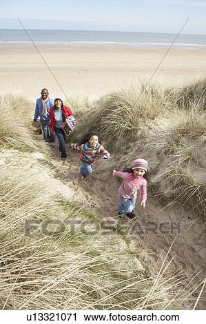 Stock Image - Family Walking Along Dunes On Winter Beach. Fotosearch