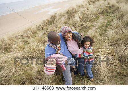 Stock Image - Family Walking Along Dunes On Winter Beach. Fotosearch