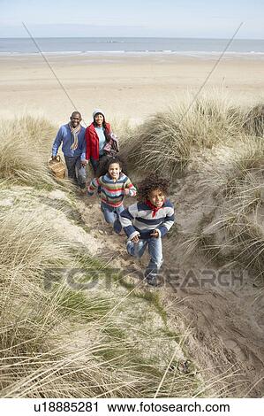 Stock Image - Family Walking Along Dunes On Winter Beach. Fotosearch