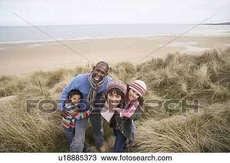 Stock Image - Family Walking Along Dunes On Winter Beach. Fotosearch