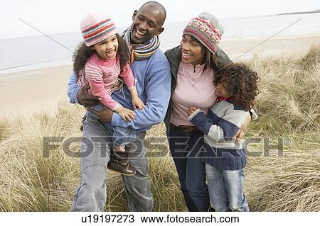 Stock Image - Family Walking Along Dunes On Winter Beach. Fotosearch