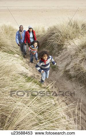 Stock Image - Family Walking Along Dunes On Winter Beach. Fotosearch