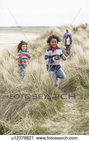 Stock Photo - Family Walking Along Dunes On Winter Beach. Fotosearch
