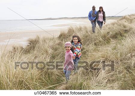 Stock Photography - Family Walking Along Dunes On Winter Beach. Fotosearch
