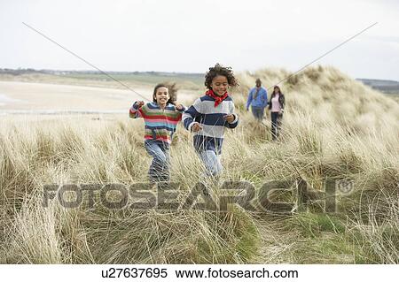 Stock Photography - Family Walking Along Dunes On Winter Beach. Fotosearch