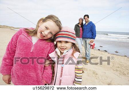 Stock Image - Family Walking Along Winter Beach. Fotosearch