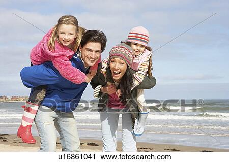 Stock Image - Family Walking Along Winter Beach. Fotosearch