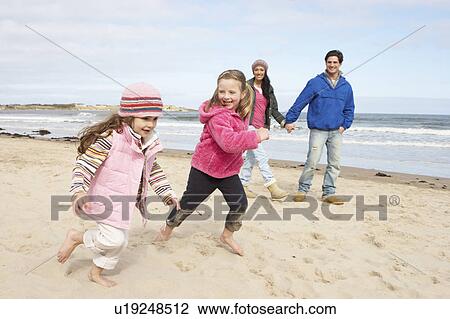 Stock Image - Family Walking Along Winter Beach. Fotosearch