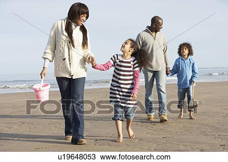 Stock Image - Family Walking By Sea On Winter Beach. Fotosearch