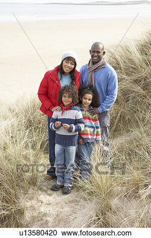 Stock Image - Family Walking In Dunes On Winter Beach. Fotosearch
