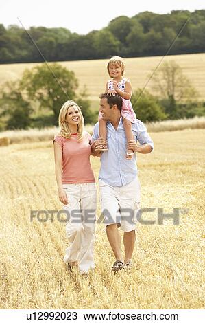 Stock Image - Family Walking Together Through Summer Harvested Field. Fotosearch
